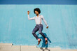© VISTA by Westend61 - Stylish man jumping in the air in front of blue wall