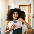© aLListar/peopleimages.com - Excited, happy hug and present for birthday of girl friends and smile from kindness. Surprise, gift and female person at home with giving in lounge with celebration, congratulations and package