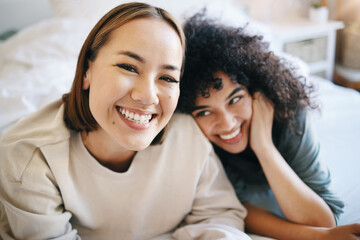 Sticker - Love, happy and portrait of lesbian couple relaxing on bed for bonding together on a weekend. Smile, romance and young interracial lgbtq women resting in the bedroom of modern apartment or home.