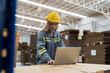 © amorn - Female warehouse worker working and inspecting quality of cardboard in corrugated carton boxes warehouse storage. Female worker checking quality of barcodes on cardboard