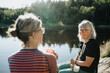 © Johnér - Two senior women sitting on rock at lakeshore