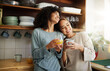© aLListar/peopleimages.com - Coffee, orange juice and happy lesbian couple in home, bonding and communication. Drink tea, gay women and girls smile in the morning at breakfast together in interracial relationship, care and LGBT