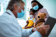© Marko Geber - Senior pediatrician entertaining his young patient with a tablet in a medical office