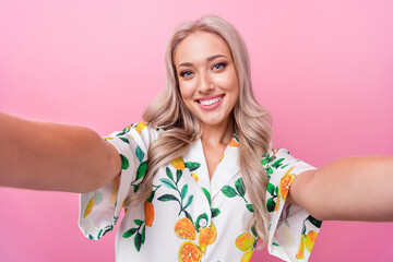 Wall Mural - Portrait of toothy beaming adorable woman with wavy hairstyle wear stylish print shirt making selfie isolated on pink color background