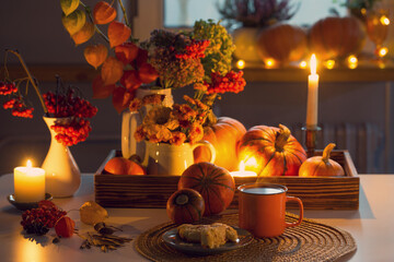 Wall Mural - orange cup of tea and autumn decor with pumpkins, flowers and burning candles on table