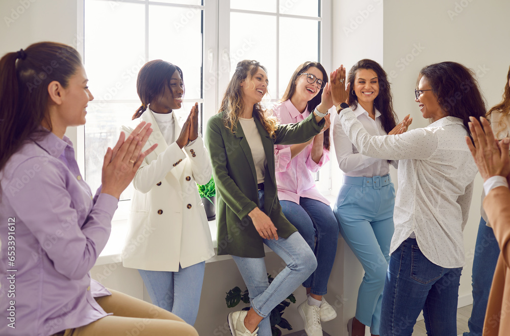 Happy women colleagues giving high five at meeting at office ...