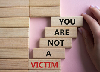 You are not your a victim. Wooden blocks with words You are not a victim. Beautiful pink background. Businessman hand. Business and You are not a victim. Copy space.