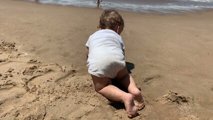 Wall Mural - Infant baby crawling at the beach to the water ocean