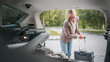 © Miljan Živković - mature blonde woman travel take stuff belongings from the back of car
