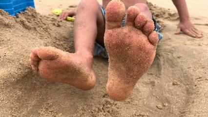 Wall Mural - Child moving feet feeling happy at beach, infant foot and toes at shore