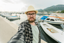 Traveller millennial man taking selfie of luxury yachts marine during sunny day - travel and videocall and blogging concept