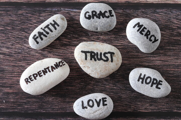 Wall Mural - Trust, mercy, faith, grace, love, repentance, and hope handwritten words on stones. Top view. Christian foundation and obedience to God Jesus Christ, biblical concept.