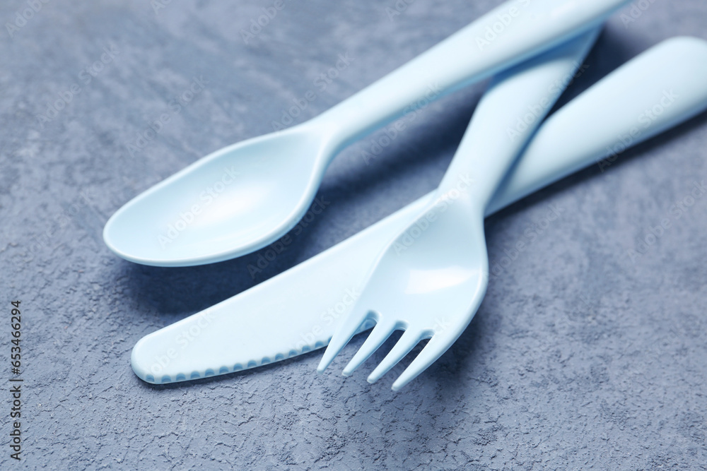 Plastic eating utensils for baby on grunge blue background