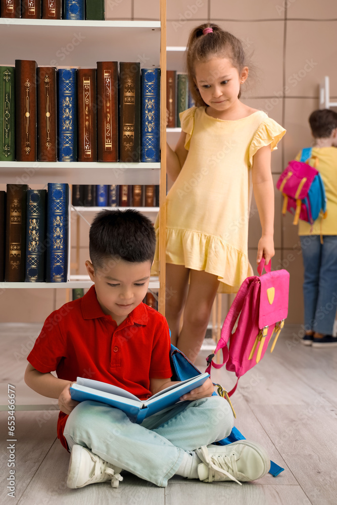 Cute little boy reading book in library