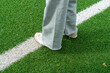 Close up of girl's feet walking on green artificial turf football field