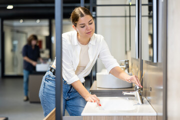 Wall Mural - Female customer choosing faucet or spigot combination set for water supply