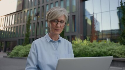 Caucasian middle aged mature woman senior old businesswoman office manager architect developer business lady working online in city typing on laptop computer outdoors busy female employer work distant