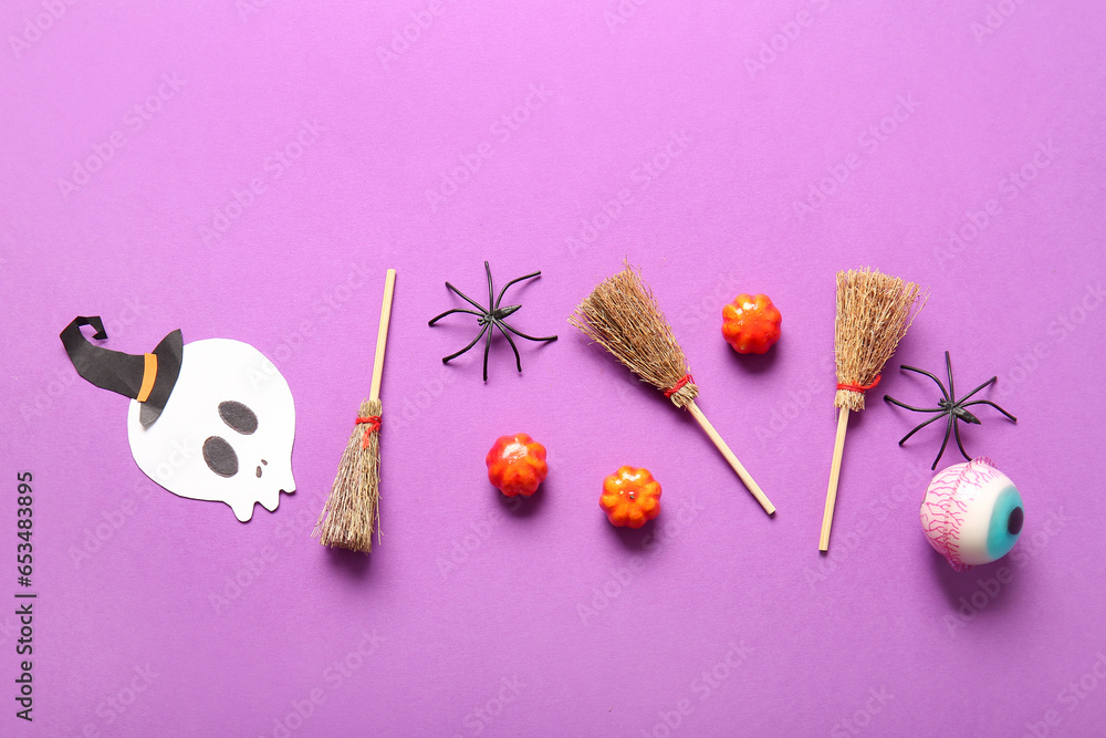 Halloween composition with brooms, pumpkins and spiders on purple background