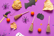 Leinwandbild Motiv Halloween composition with brooms, pumpkins, leaves and spiders on purple background
