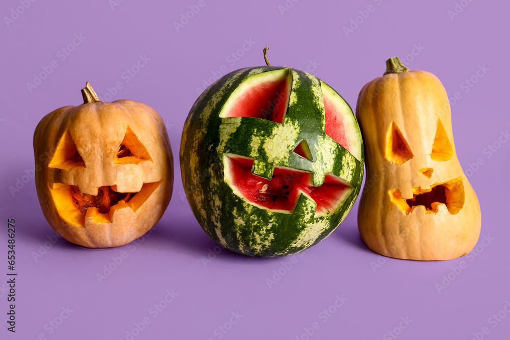 Carved pumpkins and watermelon for Halloween on lilac background