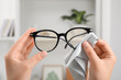 © New Africa - Woman wiping her glasses with microfiber cloth at home, closeup