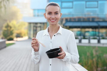 Poster - Portrait of smiling businesswoman with lunch box outdoors