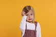 © New Africa - Portrait of embarrassed little girl on orange background