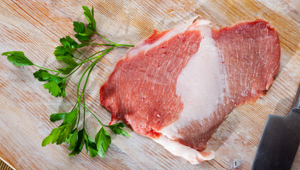 Fresh raw pork secreto fillet, special cut of Iberian pig meat and greens prepared for cooking on wooden table