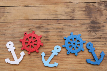 Sticker - Anchor and ship wheel figures on wooden table, flat lay. Space for text