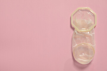 Wall Mural - Unrolled female condom on light pink background, top view and space for text. Safe sex