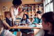 © Marko Geber - Young African American teacher looking at the work of her students in a elementary school classroom