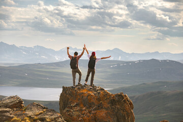 Aufkleber - Young couple of hikers with backpacks are standing at mountain top with open arms in winner pose