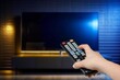 © BillionPhotos.com - Person turns on TV set with remote control, AI generated image