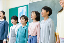 黒板の前で歌を歌う小学生たち