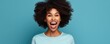 A Horizontal Shot Of A Pleased Darkskinned Female With An Afro Haircut Gesturing To An Empty Space With Both Forefingers Offering Room For Your Promotional Content Isolated Against A Blue Background