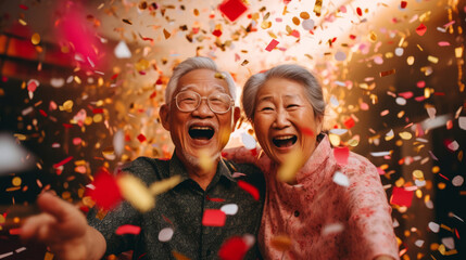 Happy senior couple celebrating birthday and in retirement with confetti and fun.