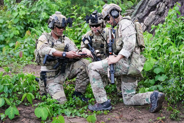 Wall Mural - Military army soldiers tactical team, commando group moving cautiously in forest area, kneeling and looking around, covering comrades, controlling sectors. Commander showing halt or stop hand signal