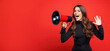 Happy woman announcing Black Friday offers through megaphone on a red background with copy space. Promotional marketing discount and online shopping concept