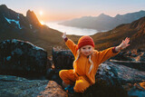 Fototapeta  - Child girl hiking in mountains travel vacations in Norway adventure outdoor active healthy lifestyle 4 years old kid happy raised hands enjoying midnight sun landscape