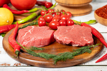 Canvas Print - Beef round slice on wood background. Raw beef round with herbs and spices