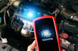 © BLKstudio - Car engine scanning with wireless technical tool, OBD2 scanner tool in a mechanic hand with a car engine compartment blurred on background, Car maintenance service concept
