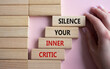 Silence your inner critic symbol. Wooden blocks with words Silence your inner critic. Beautiful pink background. Businessman hand. Business and Silence your inner critic concept. Copy space.