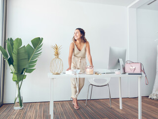 Positive ethnic lady standing at table in modern workplace