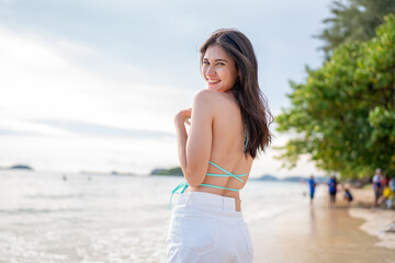 Wall Mural - Beautiful woman in blue bikini on tropical beach. Portrait of happy young woman smiling at sea. Brunette tanned girl in swimwear enjoying and walking on beach.