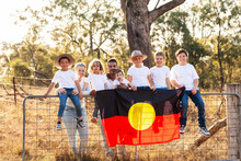 Aboriginal Family Sitting On Gate In Country Mum And Dad And Six Children Holding Flag