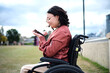 © Austockphoto - close up shot of a woman with disability sitting in a wheelchair while looking at her mobile phone