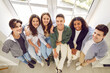 © Studio Romantic - Top view of a group of happy smiling friends high school students standing together and looking cheerful and positively at the camera in hallway. Portrait of friendly people guys and girls indoors.
