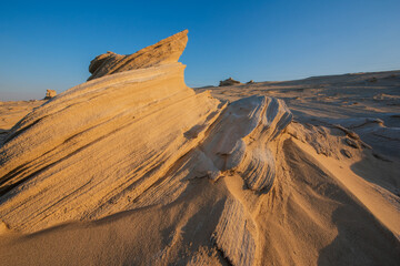 Wall Mural - Desert eroded rock pattern with clear sky during the hot sun. Desert rock formation with erosion.