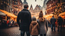 a family goes spending time at a traditional Christmas market on a winter evening. dad and children have fun in a christmas town decorated with lights. 
