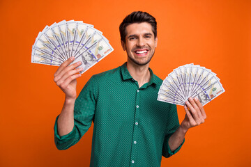 Wall Mural - Photo of funky excited man dressed green shirt rising two cash fans isolated orange color background